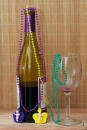 half empty wine bottle with orchid and bamboo and mardi gras beads and empty wine glass